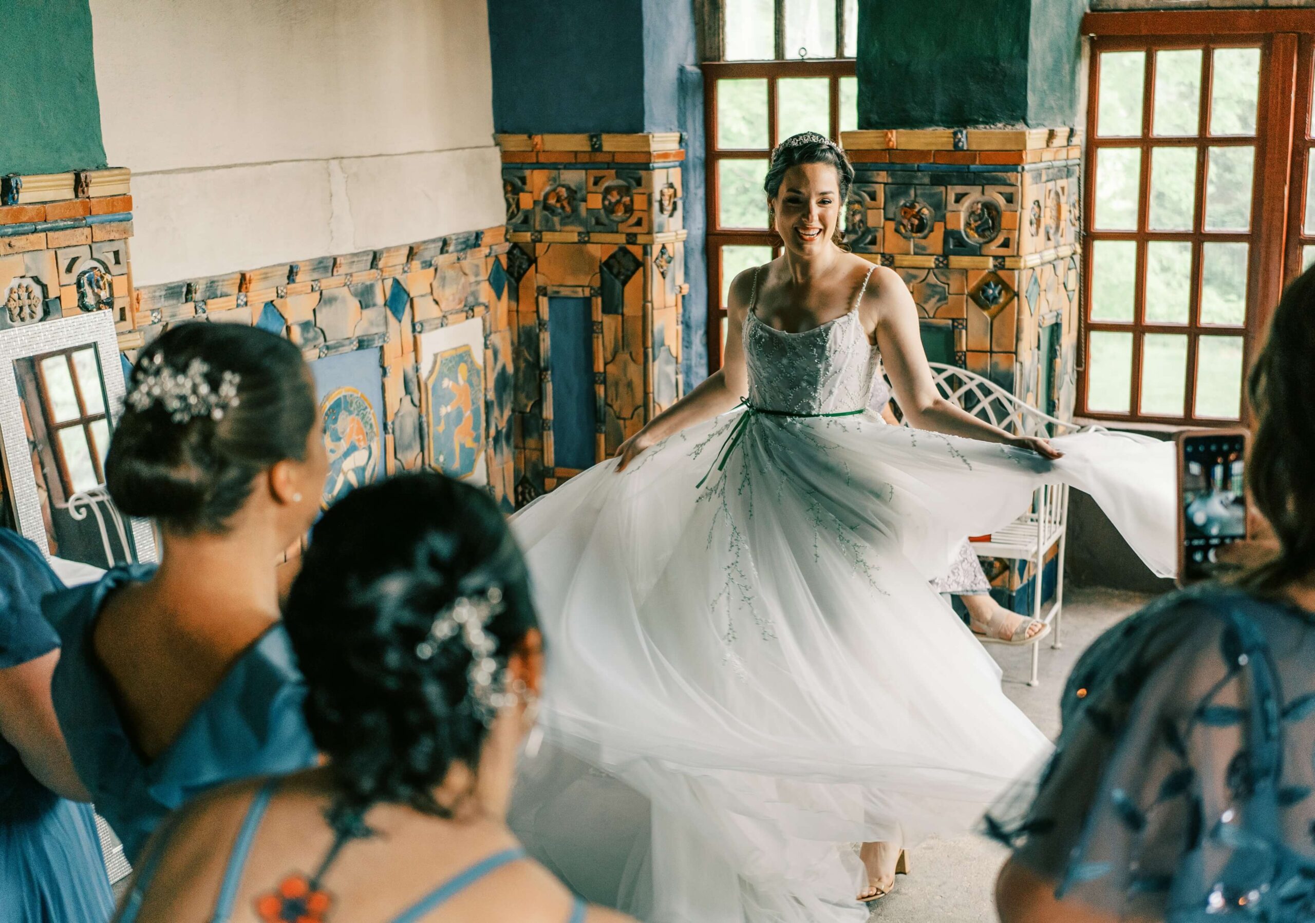 Bride in a decorated room twirling her white gown, surrounded by bridesmaids in blue dresses.