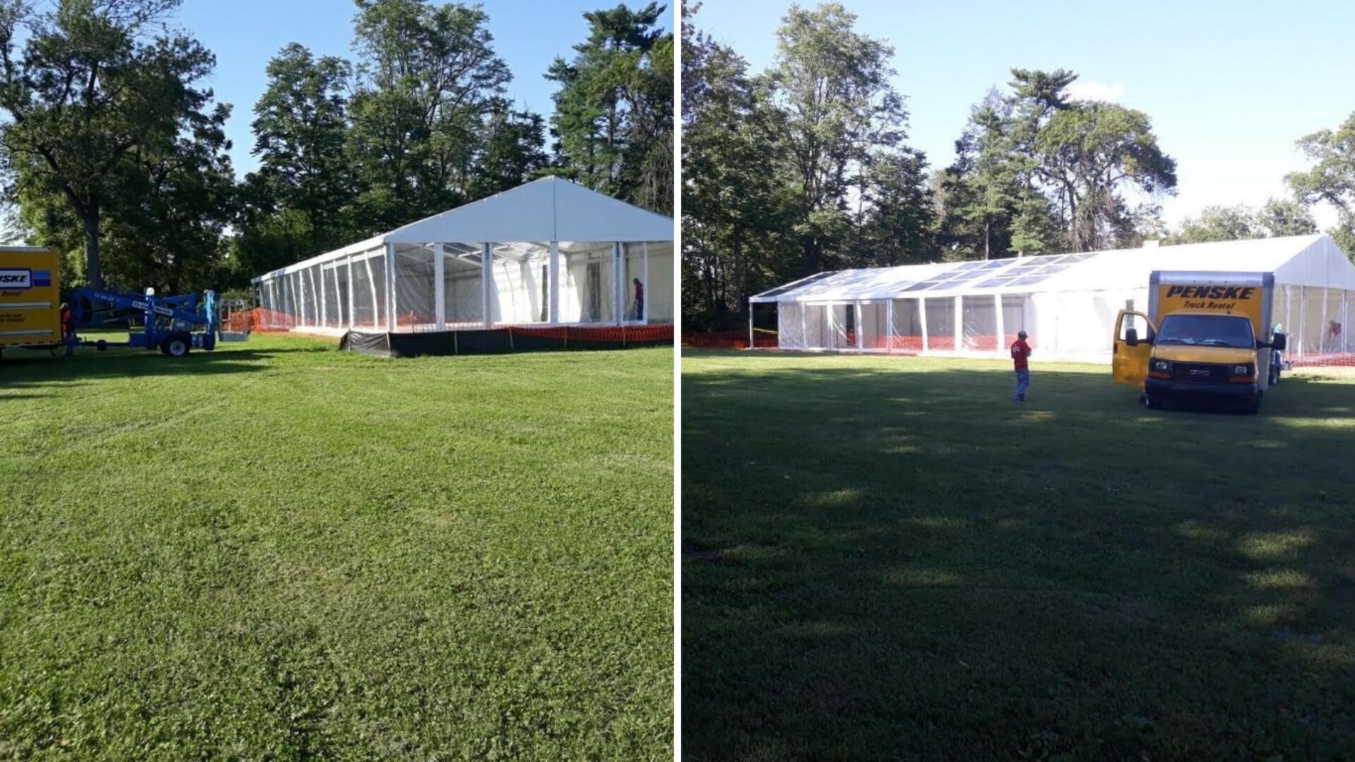 Large white tents set up on grass with surrounding trees. Trucks and equipment are visible nearby.